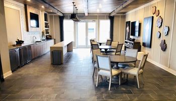 Game room with wet bar, seating, and large screen televisions